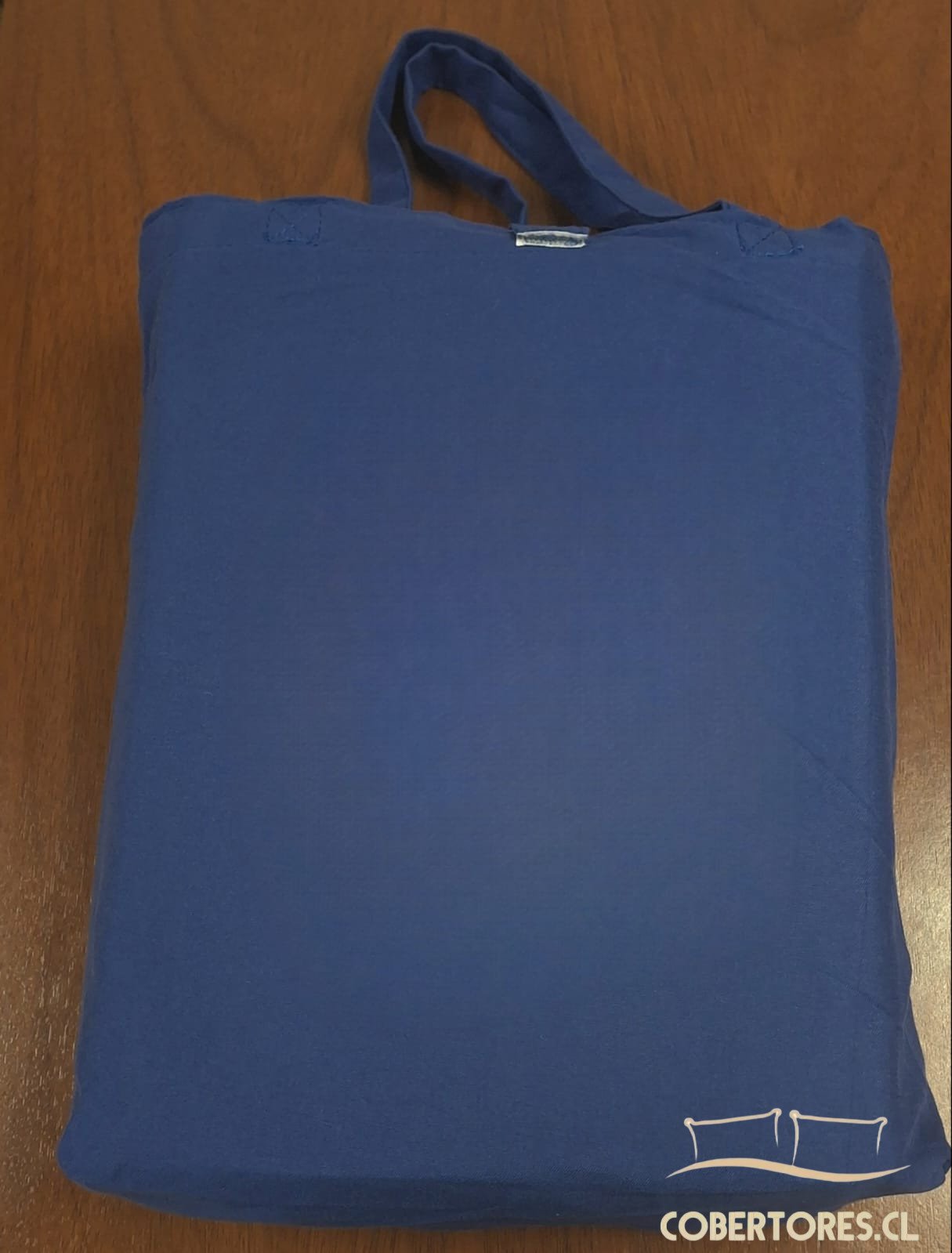 Estuche de tela de color azul vibrante que contiene un juego de sábanas premium de 800 hilos para cama de plaza y media, con detalle de asas superiores.